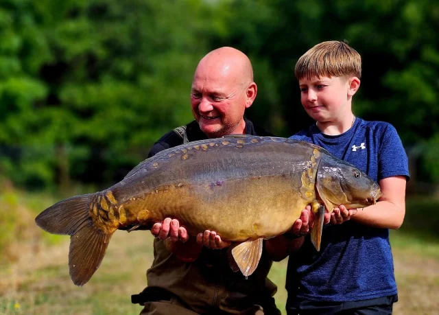Rob Smith :
We fall in love with fishing when someone takes us for that unforgettable experience. Taking young Toby for his first ever overnighter I think I may have him hooked for good! Wanting to be beat his 15lb PB i have bought him to Mollies to hopefully bag him a 20lber. Nothing is ever guaranteed but we were hopeful going into the night. Not a single bleep but seeing some fish showing this morning we put a rod in amongst them. One hour later it was away. Having saw the fish during the fight I instantly knew what fish it was. I dont know who was more nervous during the fight me or Toby. Finally slipping over the net chord i confirmed who it was. Only hours before while we enjoyed a BBQ i talked about this fish and his first bite he gets it. A new PB for Toby, Mickey Mouse at 30lb 4oz and in top top condition! I couldn't be more chuffed for him!! Happy days!! 😁🎣#30 #ls #syndicate #arrowmeadowfishery #carpfishing #gofishing #youthfishing #kidsfishing #greatoutdoors #getkidsoutdoors